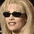 Static pixelated image of a person with long blonde hair wearing dark sunglasses and visible facial features including mouth, nose, and eyes.