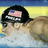 Pixelated image of a person wearing a black cap with an American flag patch, light-colored shirt, and sunglasses against a blue-yellow gradient background.
