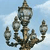 A pixelated static image of a metallic streetlamp with multiple arms against a light blue sky background.
